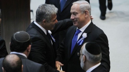 Il leader di "Yesh Atid" Yair Lapid (a sinistra) stringe la mano al primo ministro Benjamin Netanyahu durante l'apertura dei lavori della Knesset lo scorso 5 febbraio (foto Flash90)