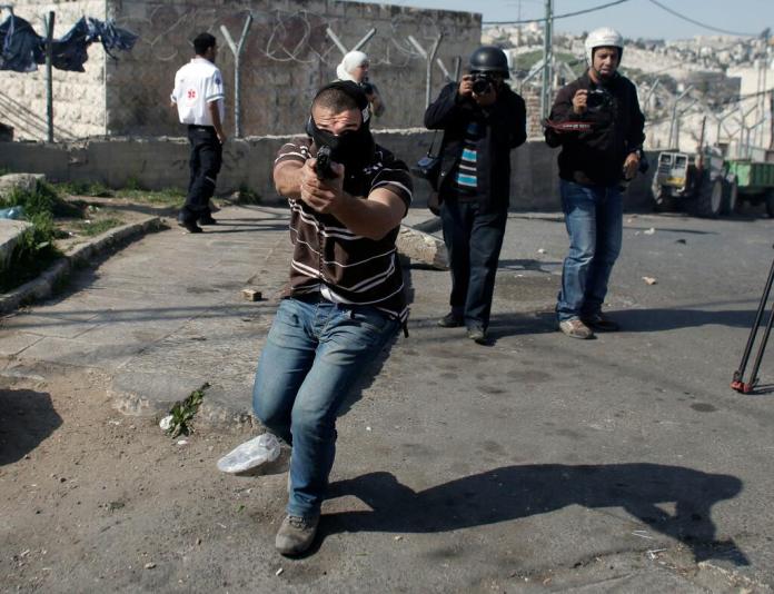 Il poliziotto israeliano con la pistola puntata contro il reporter dell'Afp (foto di Ahmad Gharabli/Afp)