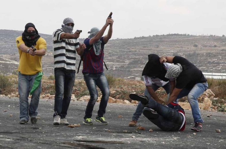 Alcuni agenti israeliani con le pistole in mostra e un paio di colleghi mentre picchiano un palestinese che poco prima aveva lanciato pietre a Beit El, alla periferia di Ramallah, in Cisgiordania, il 7 ottobre 2015 (foto di Abbas Momani / Afp)