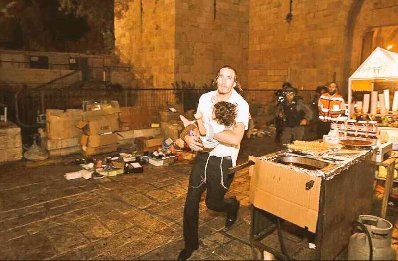 Un israeliano porta via un bimbo dalla scena del duplice omicidio nella città vecchia di Gerusalemme il 3 settembre 2015 (foto via Twitter)