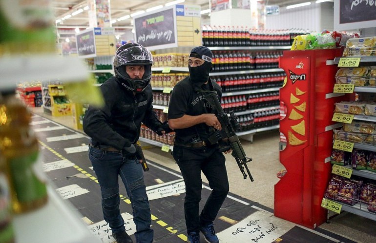 Due poliziotti controllano tra gli scaffali di un supermercato di Gerusalemme dove si nasconde un palestinese che ha appena accoltellato un'israeliana 70enne (foto Reuters)